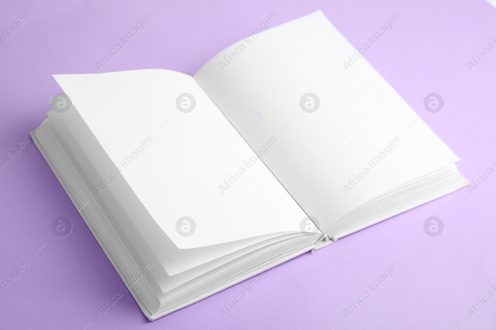Photo of Open book with blank pages on violet background