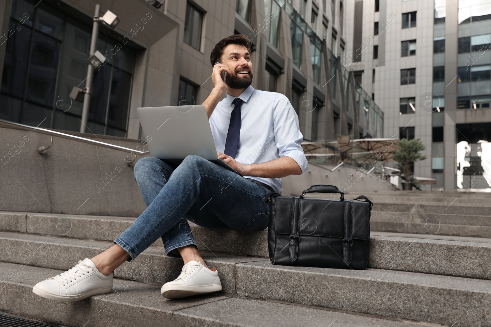 Photo of Handsome man working with laptop on city street