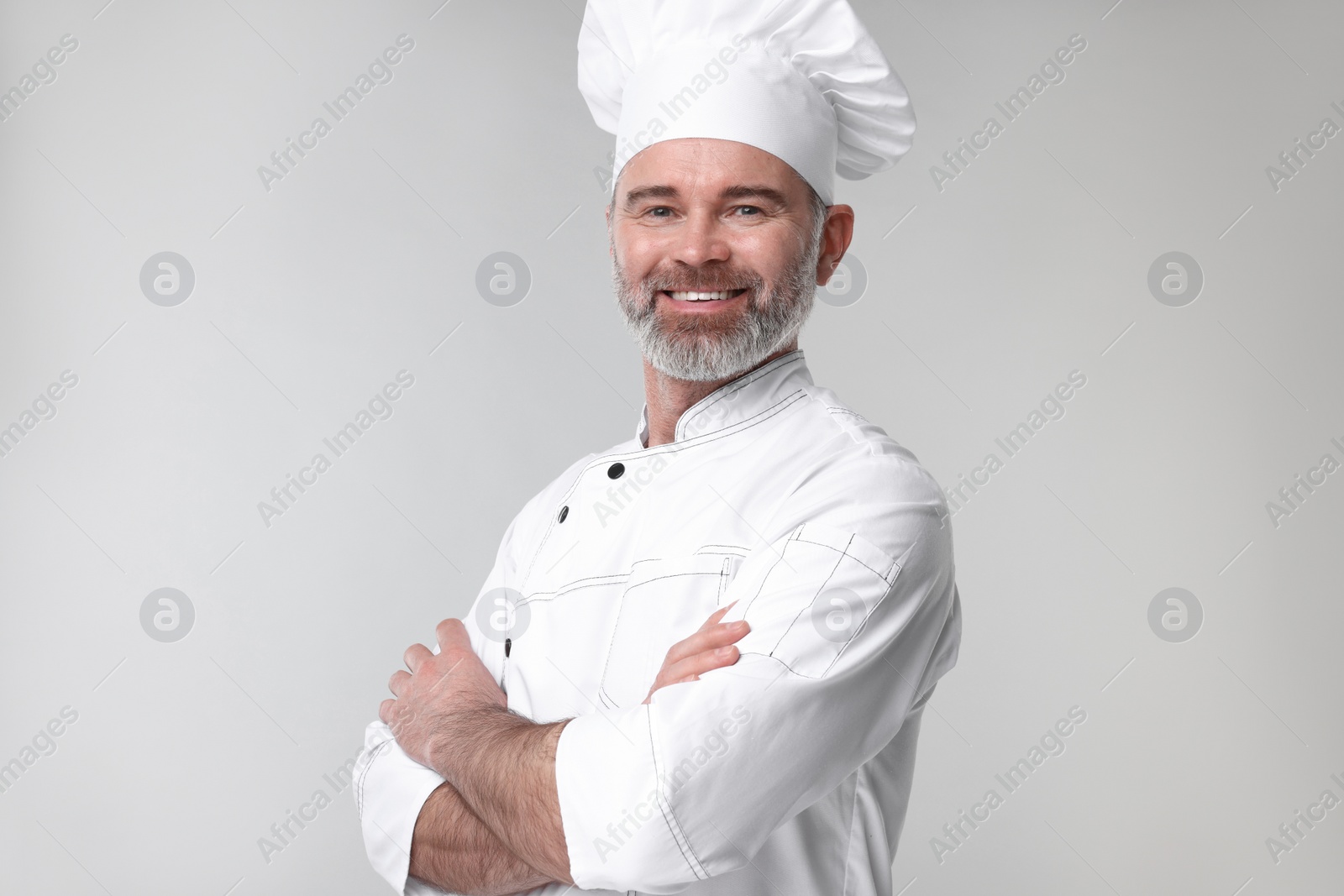 Photo of Happy chef in uniform on grey background