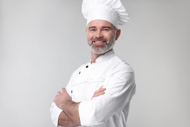 Happy chef in uniform on grey background