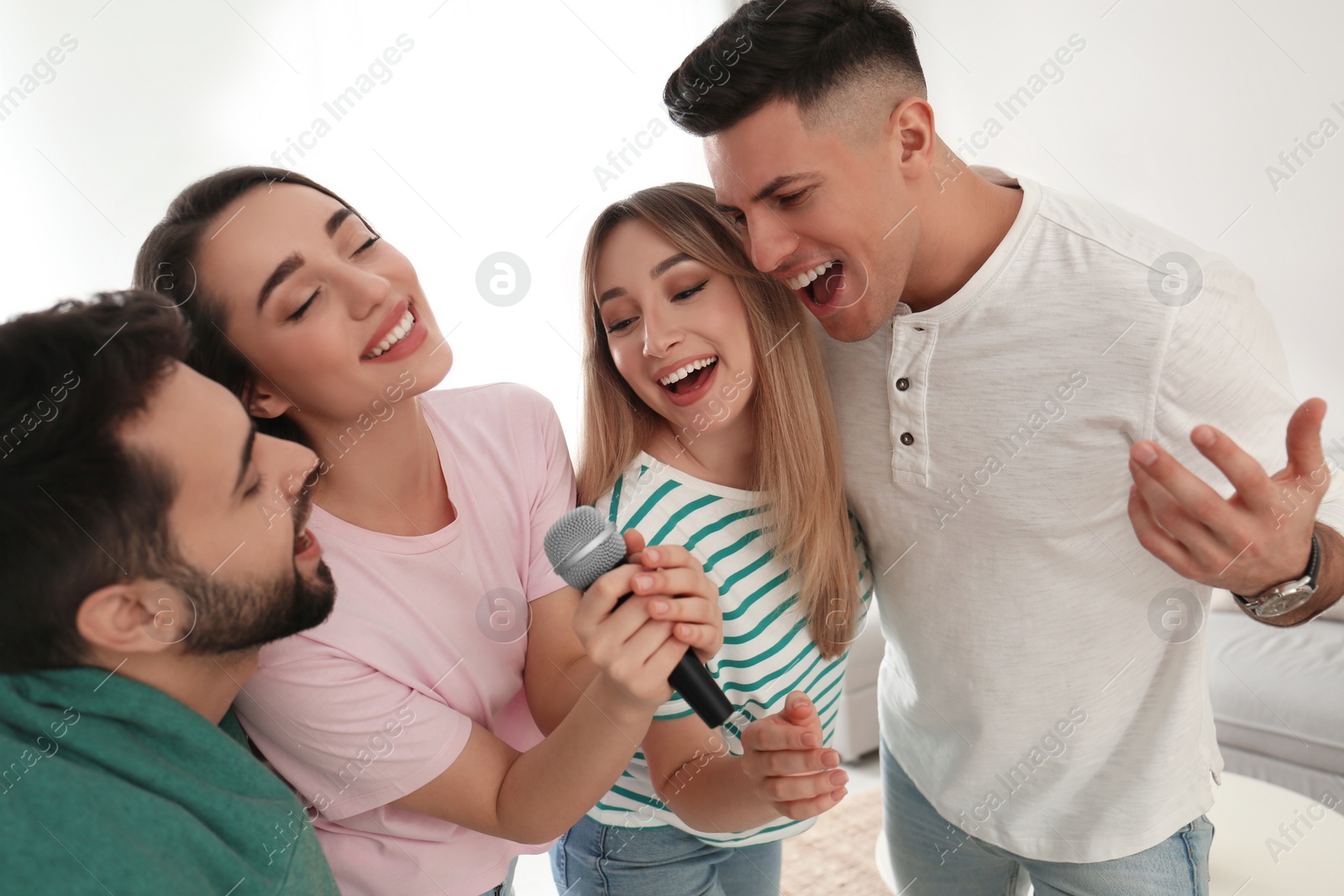 Photo of Happy friends singing karaoke together at home