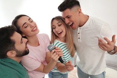 Happy friends singing karaoke together at home