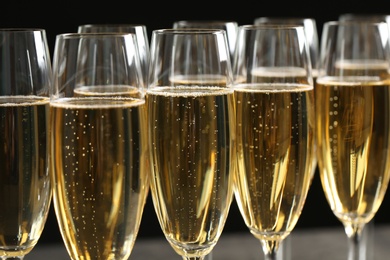 Photo of Many glasses of champagne on dark background, closeup