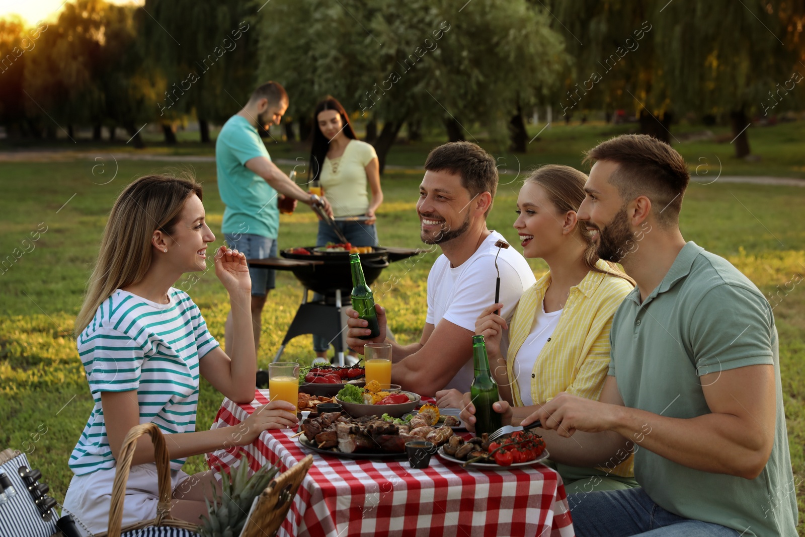 Photo of Happy friends with drinks and food at barbecue party in park