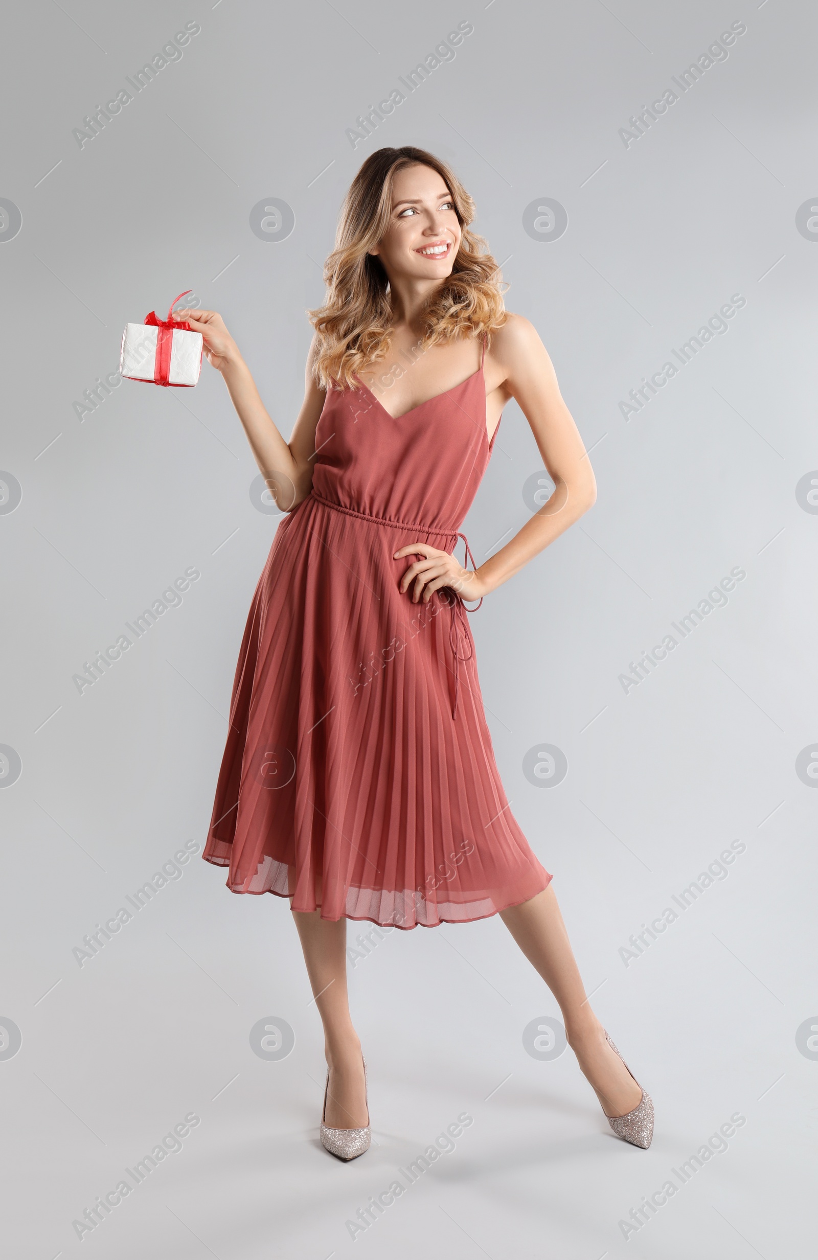 Photo of Beautiful young woman with Christmas present on light grey background