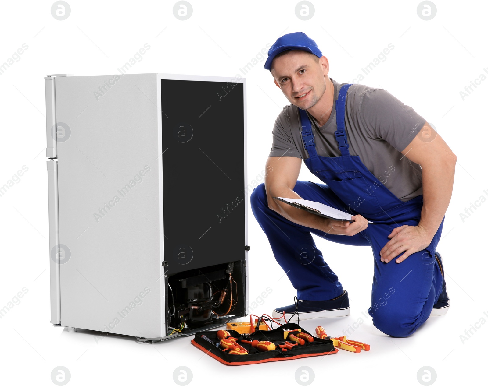 Photo of Male technician with clipboard and tools near broken refrigerator on white background