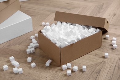 Cardboard box and styrofoam cubes on wooden floor