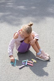 Photo of Little child drawing flower with chalk on asphalt