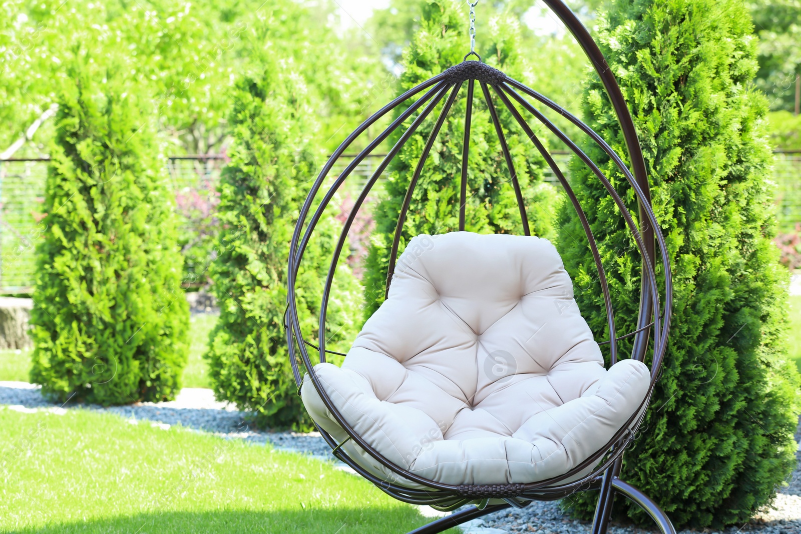 Photo of Beautiful English style garden with comfortable hanging chair on sunny day