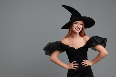 Photo of Happy young woman in scary witch costume on light grey background, space for text. Halloween celebration