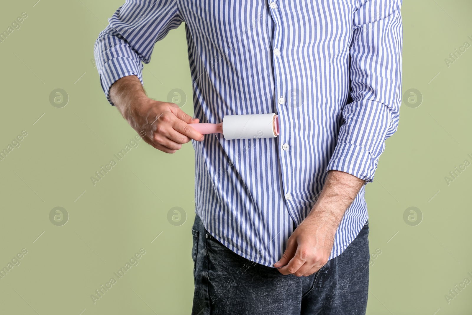 Photo of Man cleaning clothes with lint roller on light background, closeup