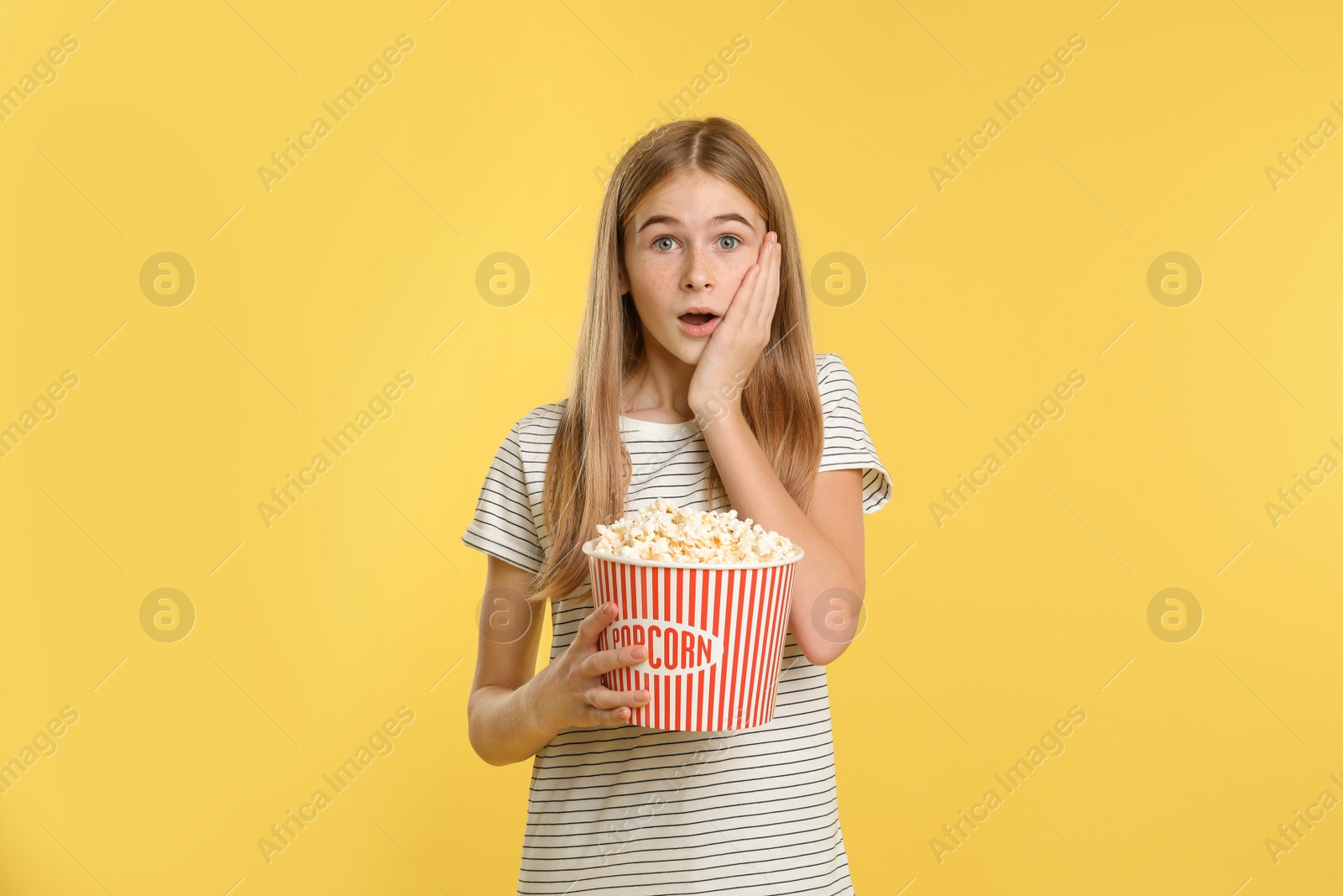 Photo of Emotional teenage girl with popcorn during cinema show on color background