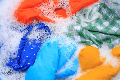 Photo of Colorful clothes in suds, top view. Hand washing laundry