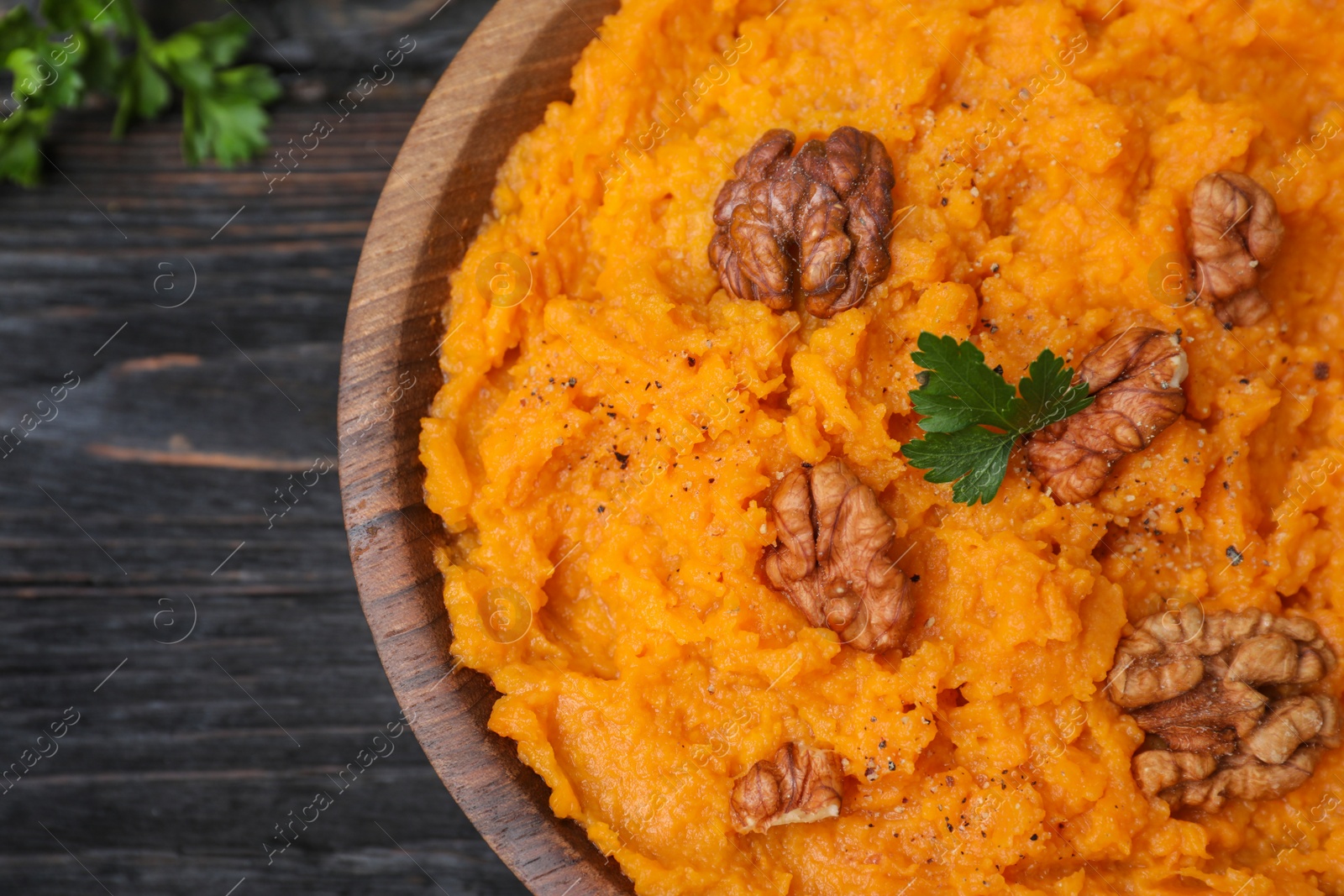 Photo of Bowl with mashed sweet potatoes on wooden table, closeup