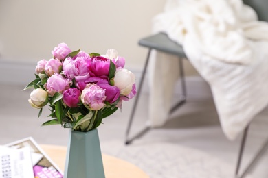 Photo of Vase with bouquet of beautiful peonies on table in room, space for text