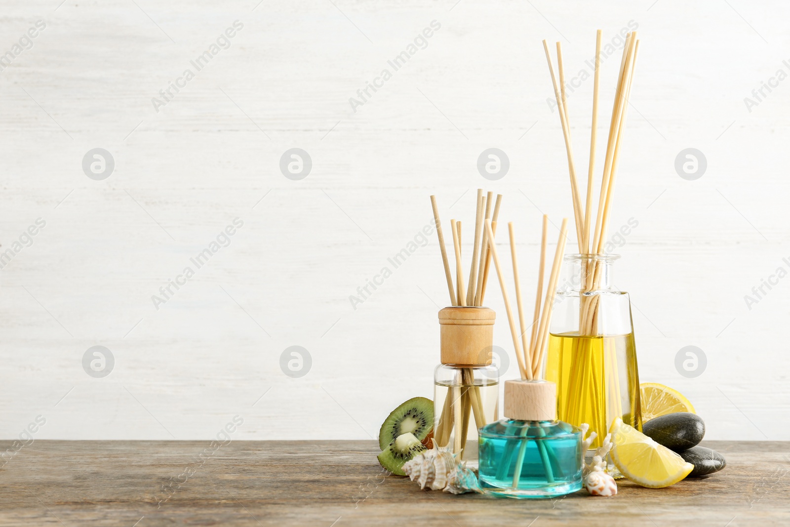 Photo of Composition with aromatic reed fresheners on wooden table against light background. Space for text