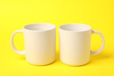 Photo of Two white ceramic mugs on yellow background