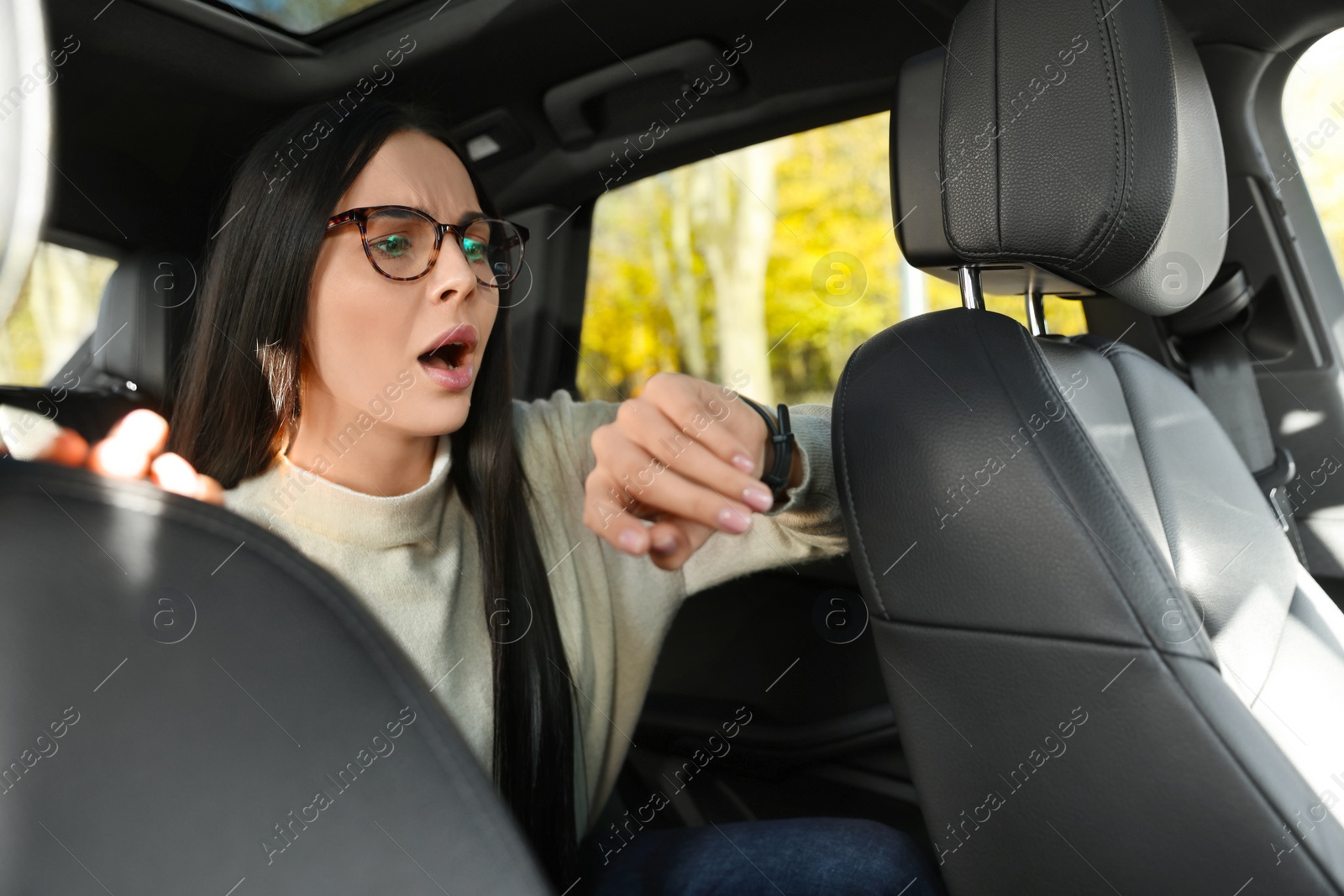 Photo of Emotional woman checking time on watch in car. Being late concept