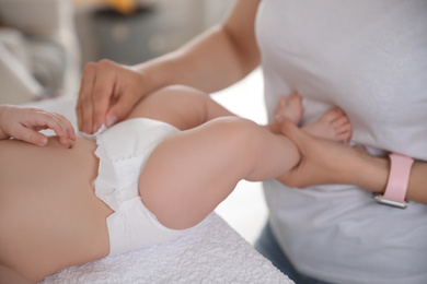 Photo of Mother changing baby's diaper on table, closeup