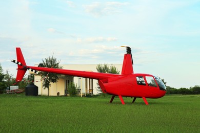 Photo of Modern red helicopter on green grass outdoors