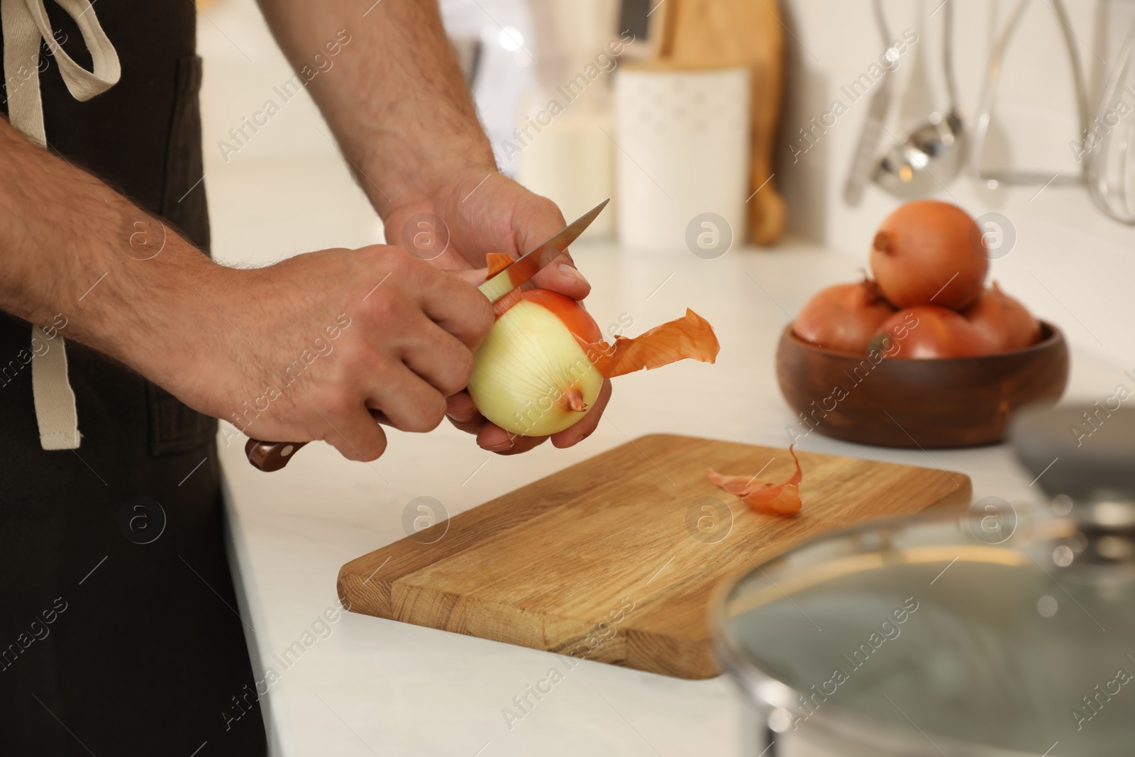 Photo of Man peeling onion at kitchen counter, closeup. Preparing vegetable