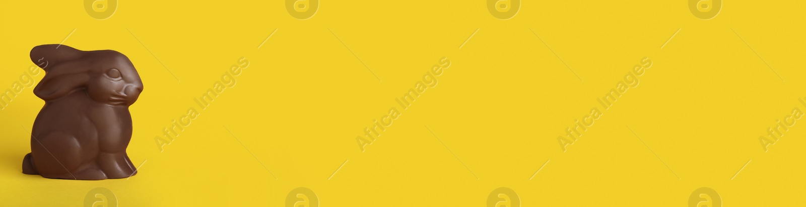 Photo of Chocolate bunny on yellow background, space for text. Easter celebration