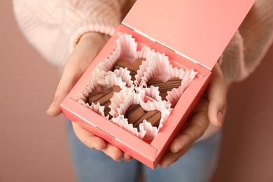 Photo of Woman with box of heart shaped chocolate candies on pink background, closeup