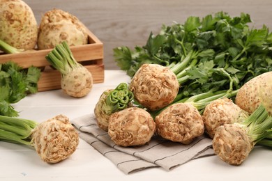 Photo of Fresh raw celery roots on white wooden table
