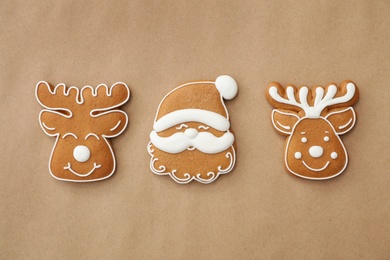 Photo of Christmas Santa Claus face and deer shaped gingerbread cookies on brown background, flat lay