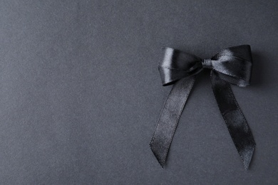 Photo of Black ribbon bow on dark background, top view with space for text. Funeral symbol
