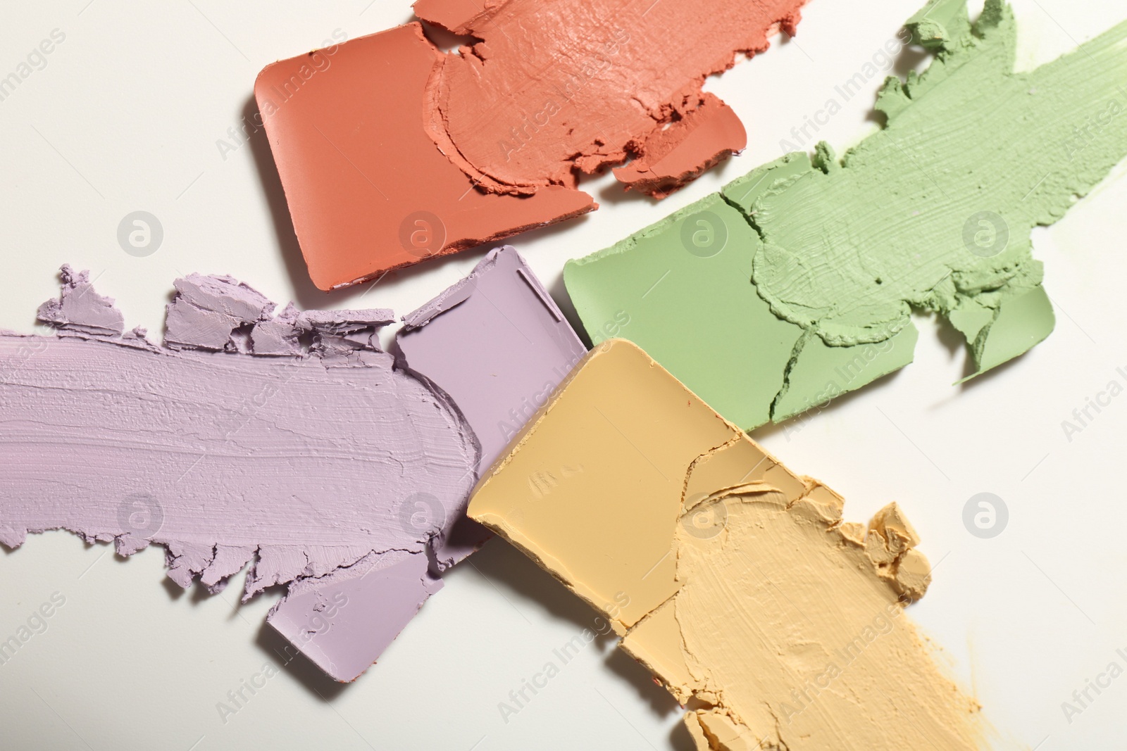 Photo of Samples of different color correcting concealers on white background, top view