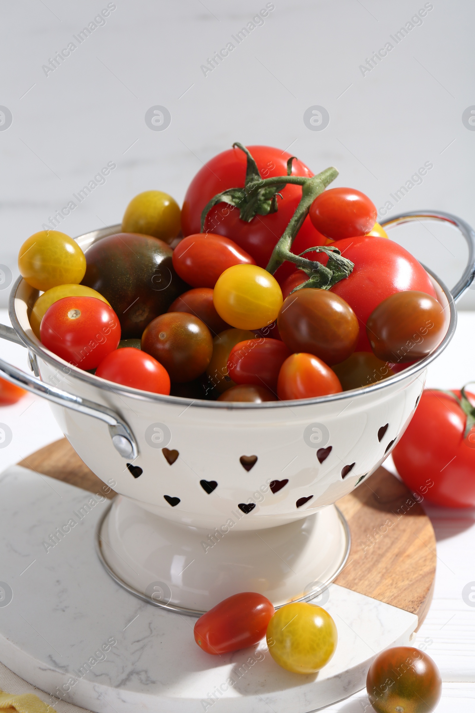 Photo of Metal colander with fresh tomatoes on table, closeup