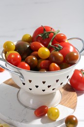 Photo of Metal colander with fresh tomatoes on table, closeup