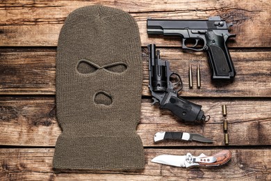 Flat lay composition with balaclava and weapons on wooden table