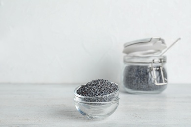 Photo of Poppy seeds in bowls on table against light background. Space for text