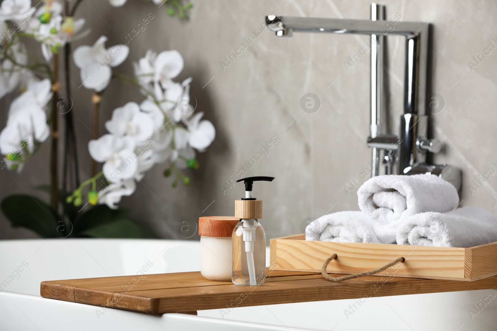 Photo of Personal care products and rolled towels on bath tray indoors