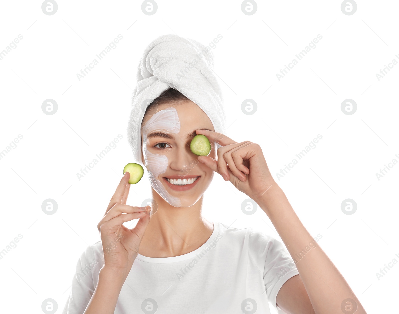 Photo of Happy young woman with organic mask on her face holding cucumber slices against white background