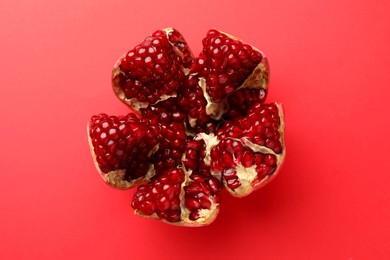 Photo of Cut fresh pomegranate on red background, top view