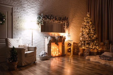 Stylish interior with beautiful Christmas tree and artificial fireplace at night