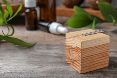 Photo of Wooden cube with needles for acupuncture on table