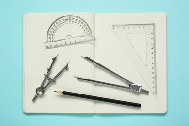 Different rulers, pencils, compasses and notebook on turquoise background, flat lay