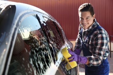 Photo of Worker cleaning automobile with sponge at car wash