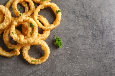 Photo of Homemade crunchy fried onion rings on color table, top view. Space for text