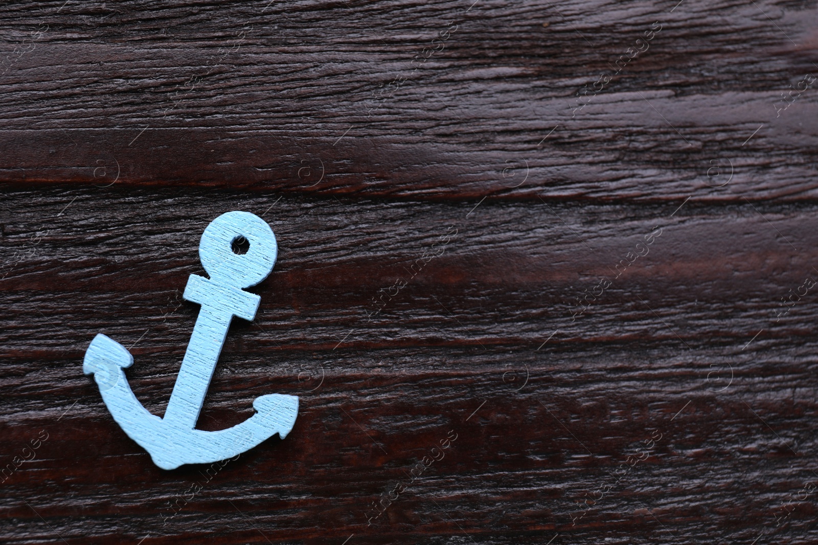 Photo of Anchor figure on dark wooden table, top view. Space for text