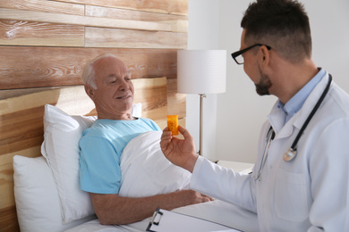 Photo of Doctor giving pills to senior patient in modern hospital