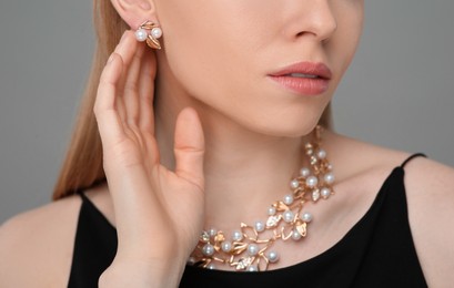 Photo of Woman with elegant jewelry on gray background, closeup