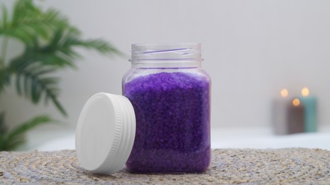 Photo of Jar with bath salt on wicker mat in bathroom