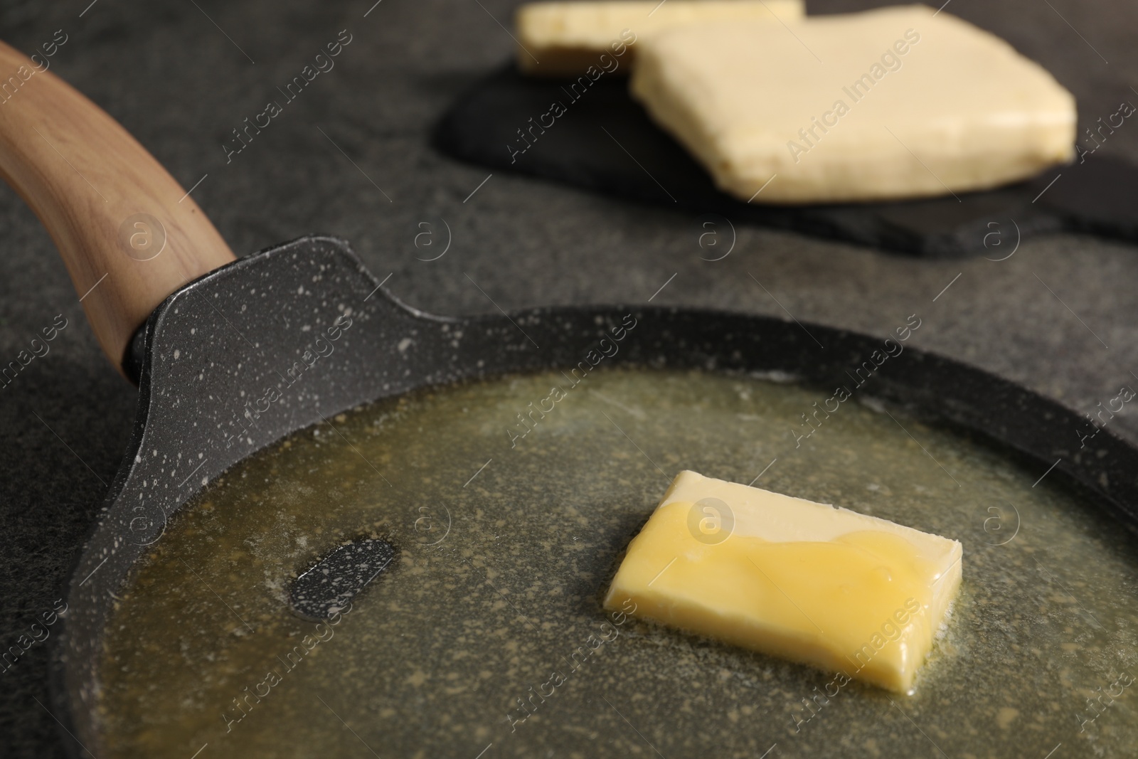 Photo of Melting butter in frying pan on grey table, closeup