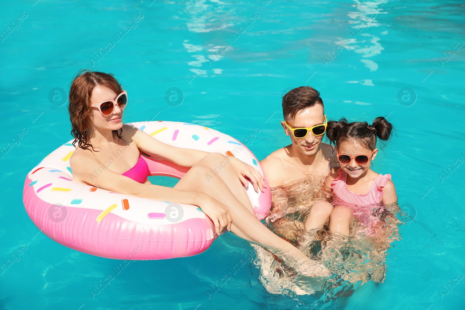 Photo of Happy family in swimming pool at resort