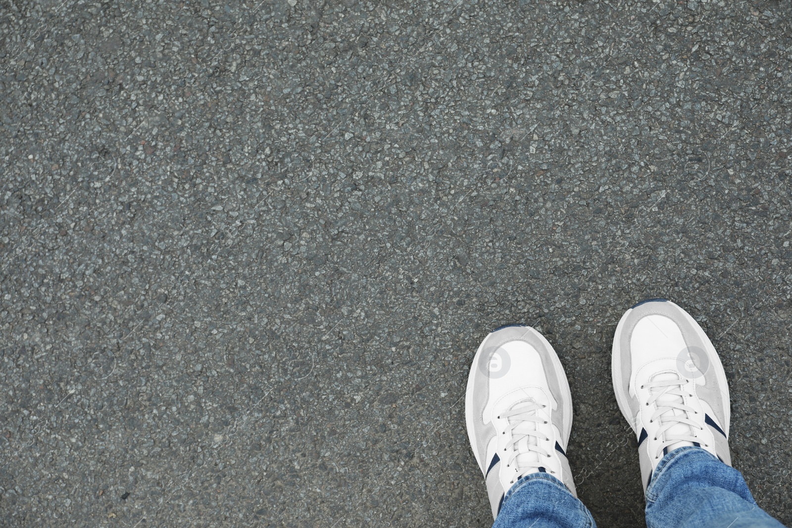 Photo of Man in sneakers standing on asphalt, top view. Space for text